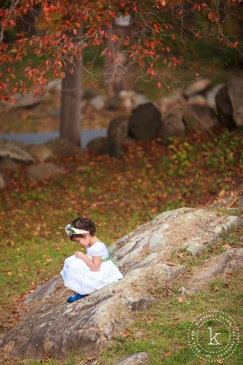 Adorable flower girl sitting on a rock